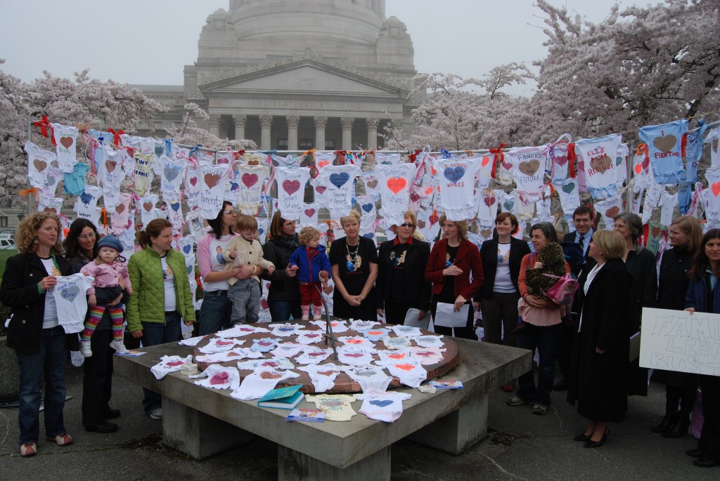 Onesies decorated by MomsRising members formed the backdrop for a 2007 Work and Family Coalition press conference outside the Washington State Capitol introducing an earlier version of paid family and medical leave.