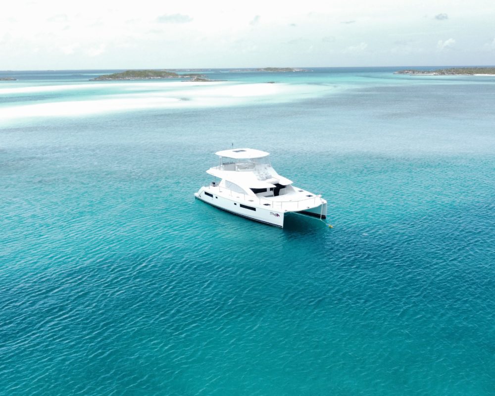 A yacht drops anchor in very clear blue water.