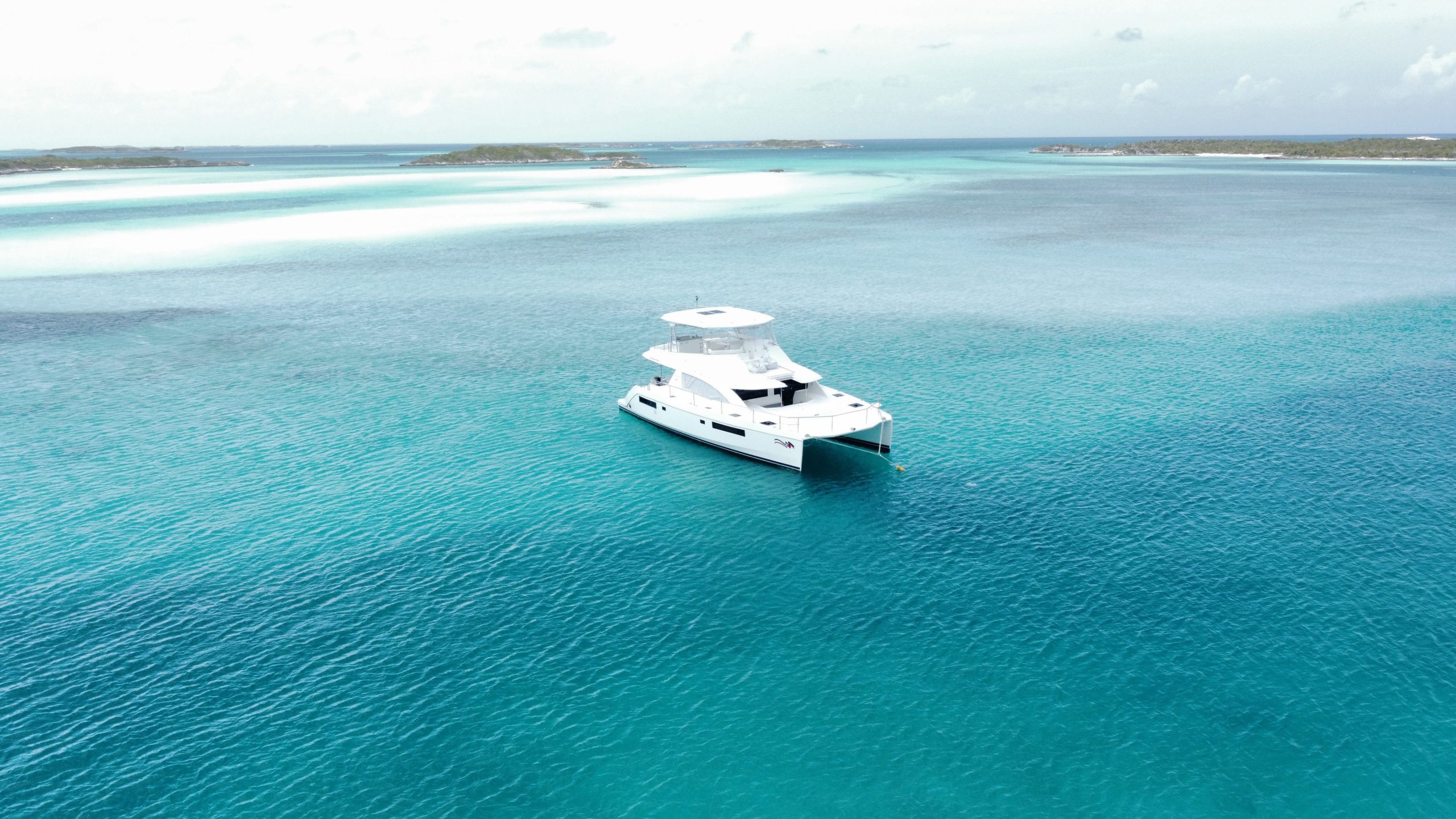 A yacht drops anchor in very clear blue water. 