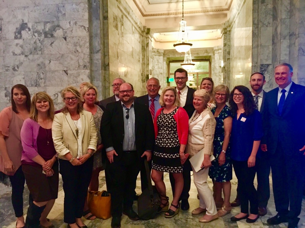 Coalition and business negotiators and the governor gather outside the Senate chamber to thank lead sponsors immediately after the Senate passed PFML. Left to right: Julia Gorton, Washington Hospitality Association; Holly Chisa, NW Grocery Association; Nancy Sapiro, Legal Voice; Lindsey Grad, SEIU 1199 (partly hidden); Brenda Wiest, Teamsters 117; Bob Battles, Association of Washington Business; Joe Kendo, Washington State Labor Council, AFL-CIO; Sen. Steve Conway, D-Tacoma; Rebecca Johnson, UFCW 21; Senator Joe Fain, R-Auburn; Senator Karen Keiser, D-Des Moines; Tammie Hetrick, Washington Retail Association; Marilyn Watkins, Economic Opportunity Institute; Maggie Humphreys, MomsRising; Nick Streuli, Washington Economic Security Department; Governor Jay Inslee.