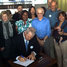 Tasha West-Baker, second from left, watches Seattle Mayor Mike McGinn sign Seattle's Paid Sick Leave bill into law.